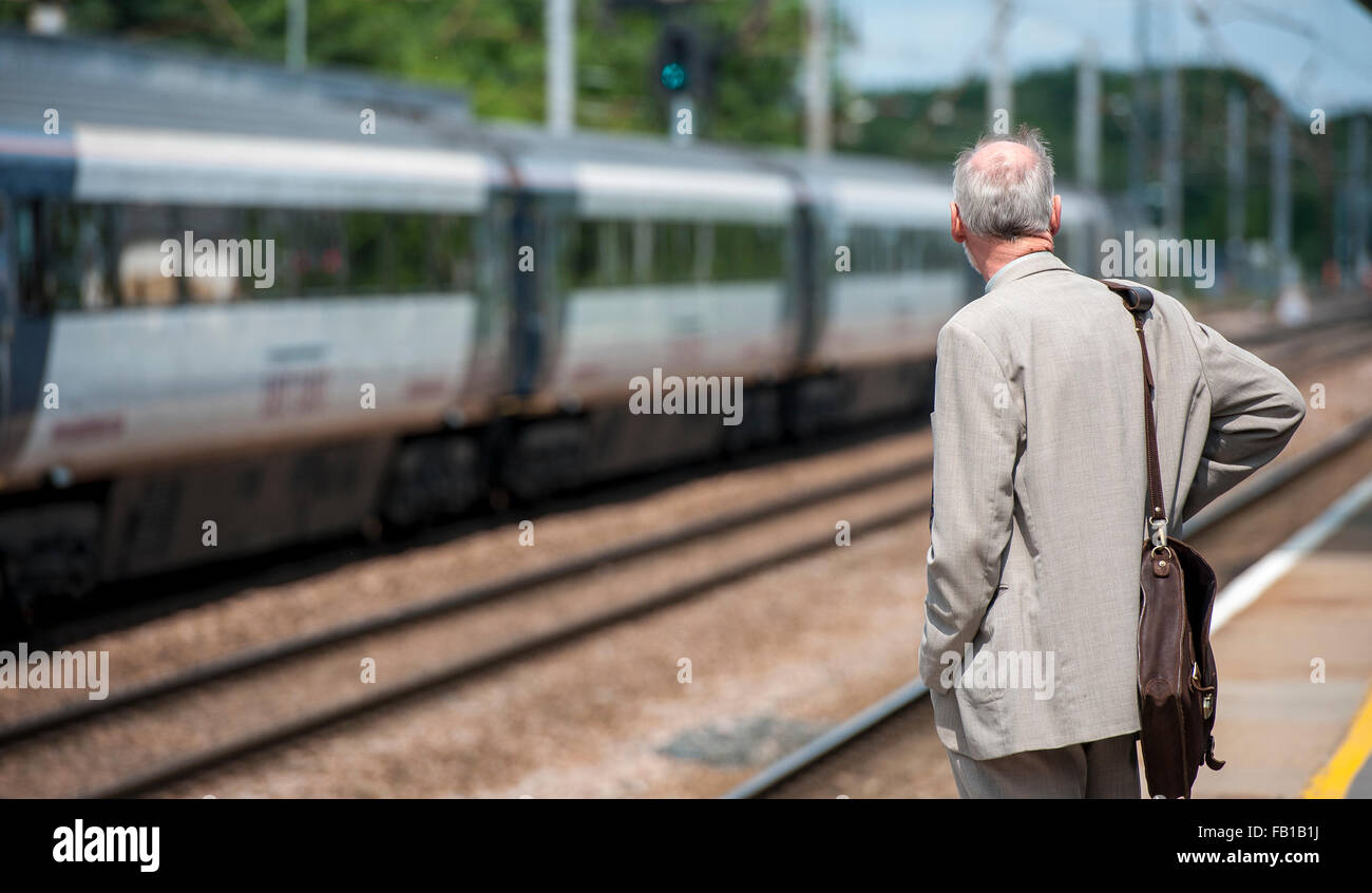 Uomo in attesa di un treno in una stazione ferroviaria nel Regno Unito. Foto Stock