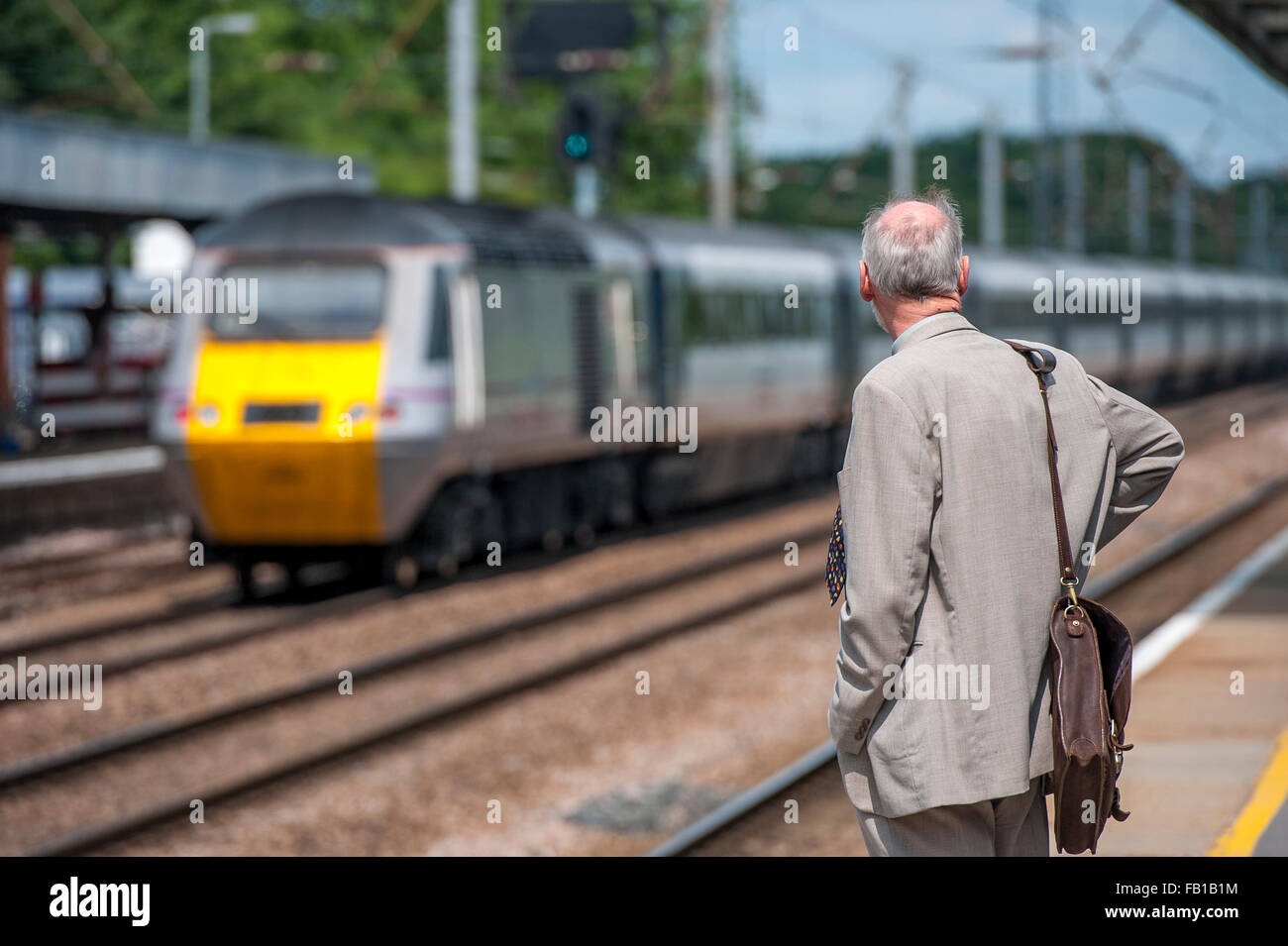 Uomo in attesa di un treno in una stazione ferroviaria nel Regno Unito. Foto Stock
