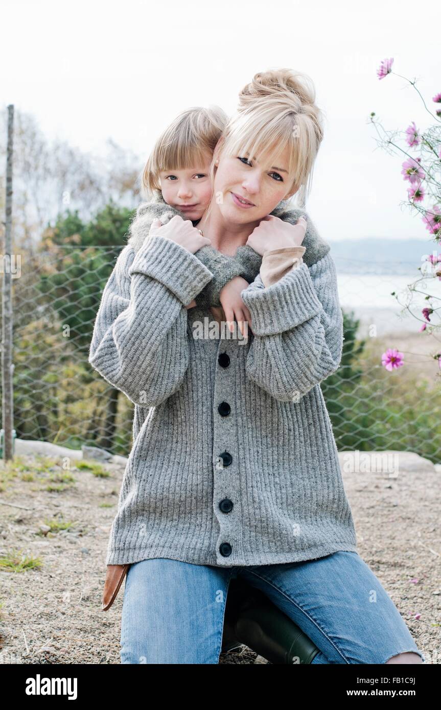 Ritratto di ragazzo con le braccia intorno a madre in giardino Foto Stock