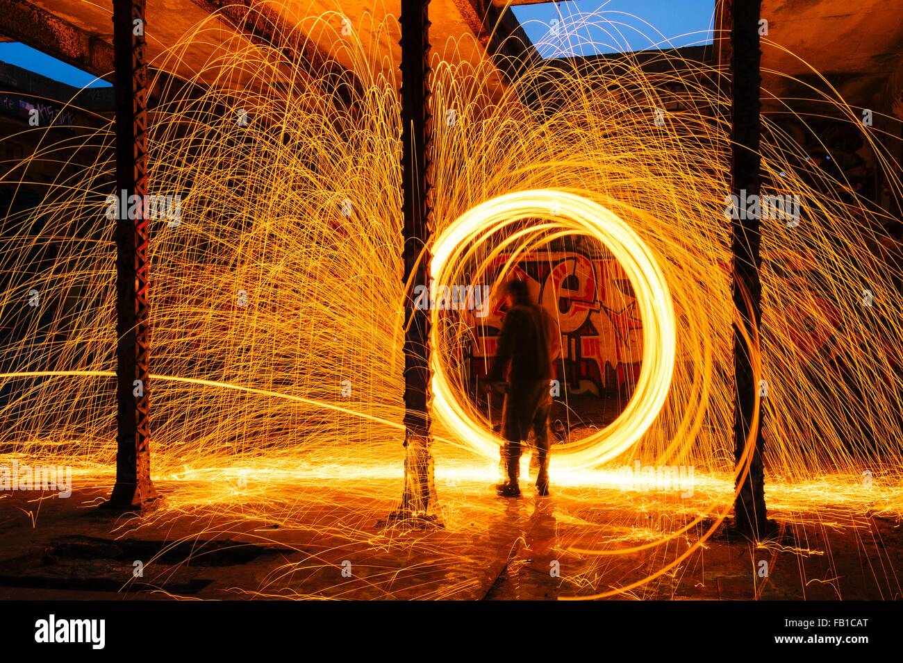 L'uomo creazione circolare scintilla dorata sentieri di luce in edificio abbandonato Foto Stock