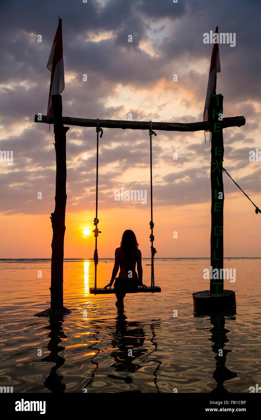 Stagliano turista femminile per rotazione guardando il tramonto sul mare, Gili Trawangan, Lombok, Indonesia Foto Stock