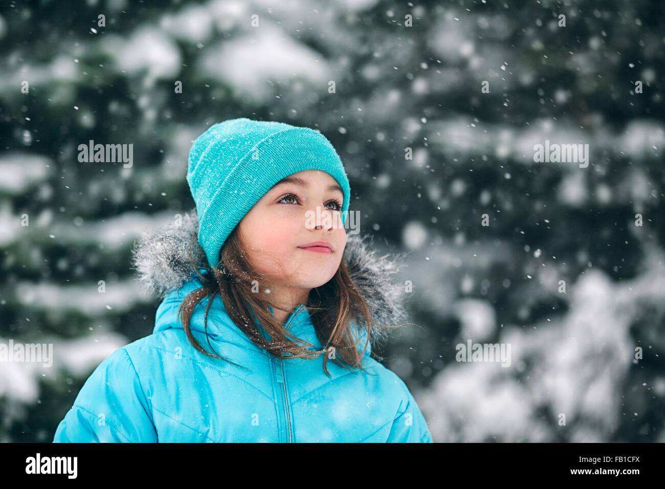 Ragazza indossando knit hat guardando lontano, nevicava Foto Stock