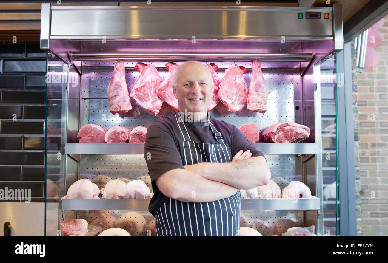 Ritratto di macellaio con i bracci ripiegati nel negozio di macellaio Foto Stock
