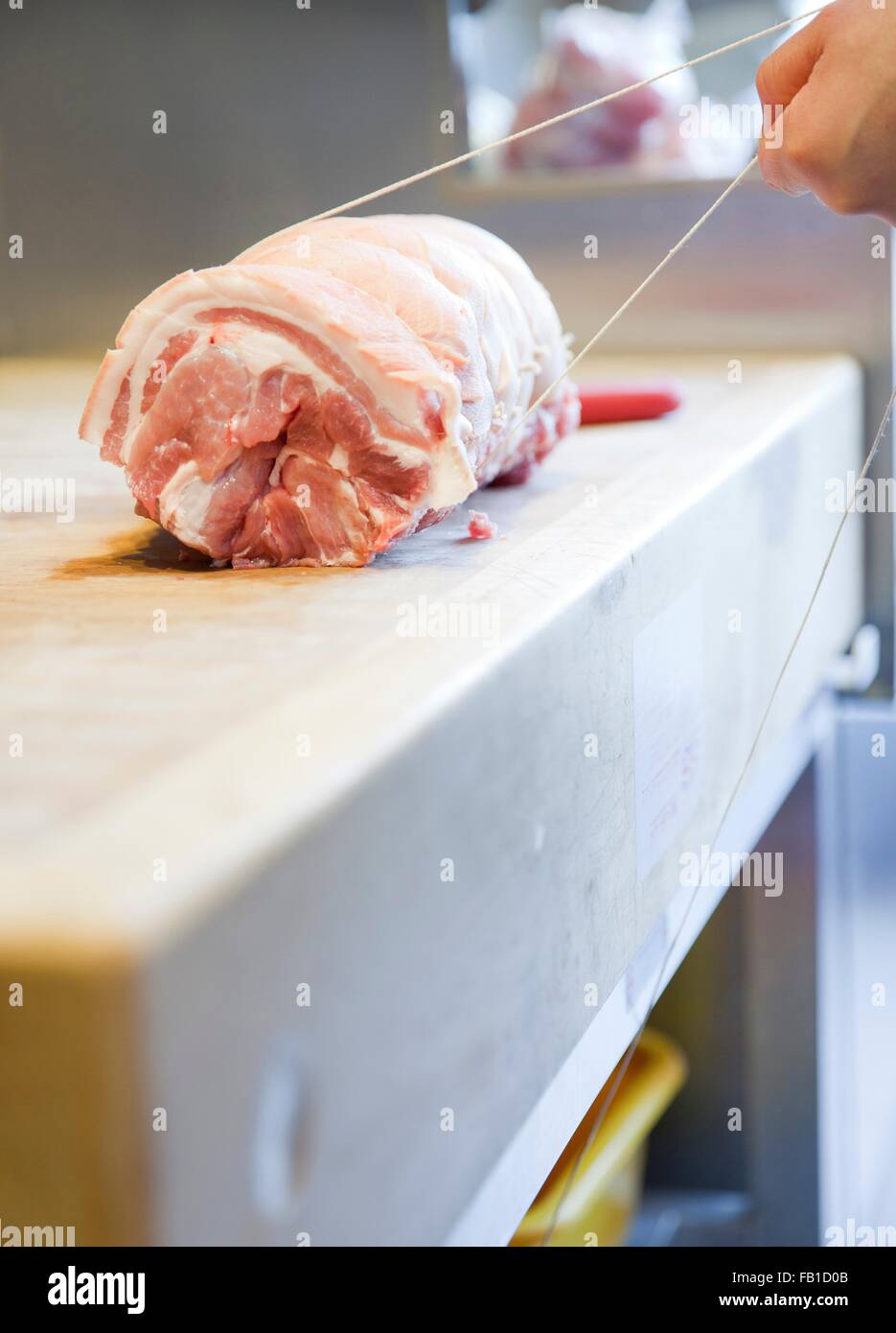 Close up dei macellai mani di carne di legatura giunto nel negozio di macellaio Foto Stock