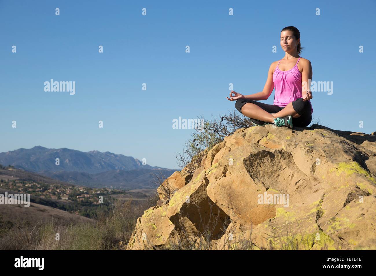 Donna matura la pratica dello yoga lotus pongono sulla collina, Thousand Oaks, California, Stati Uniti d'America Foto Stock
