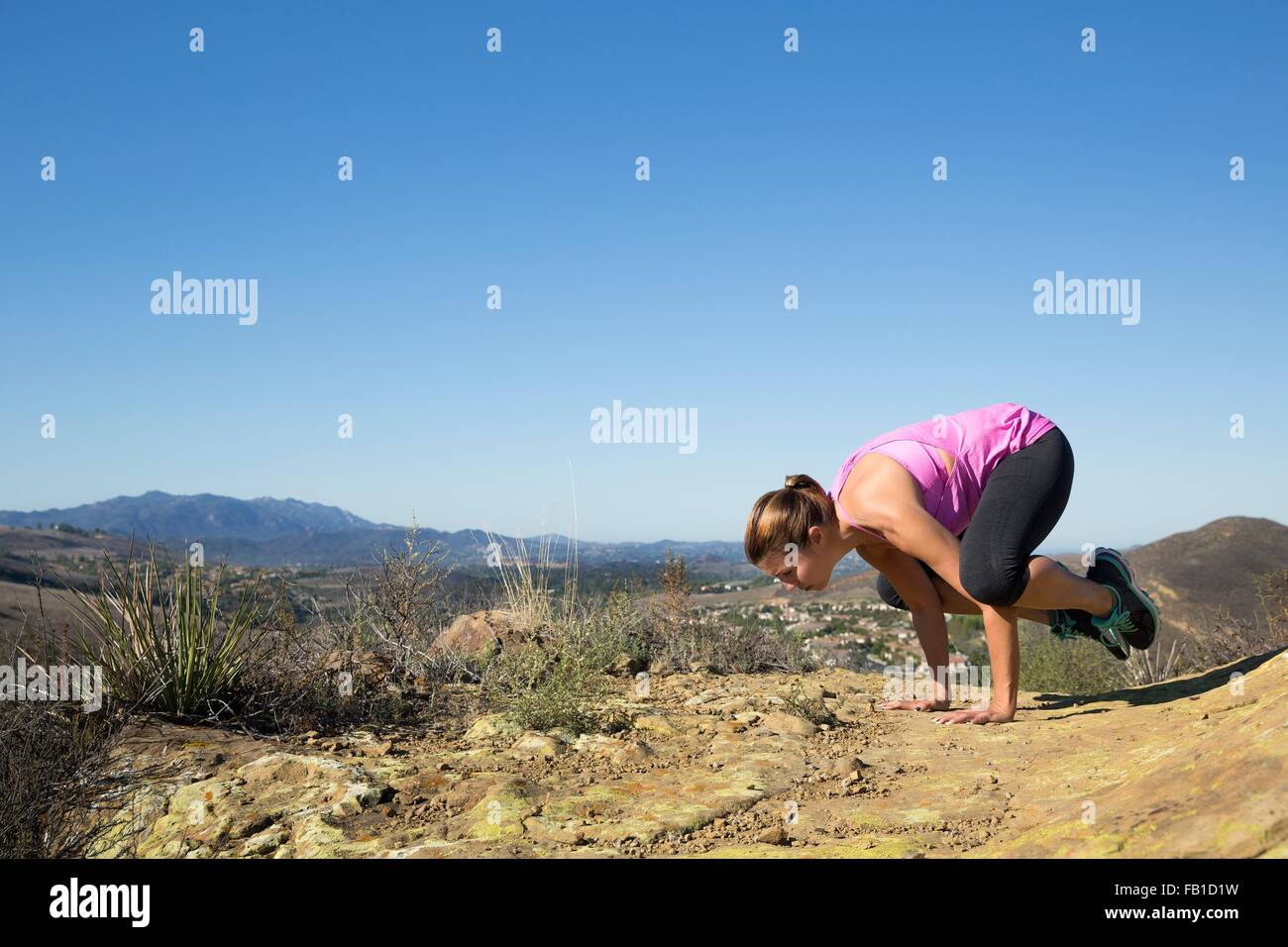 Donna matura la pratica dello yoga pone sulla cima di una collina Foto Stock