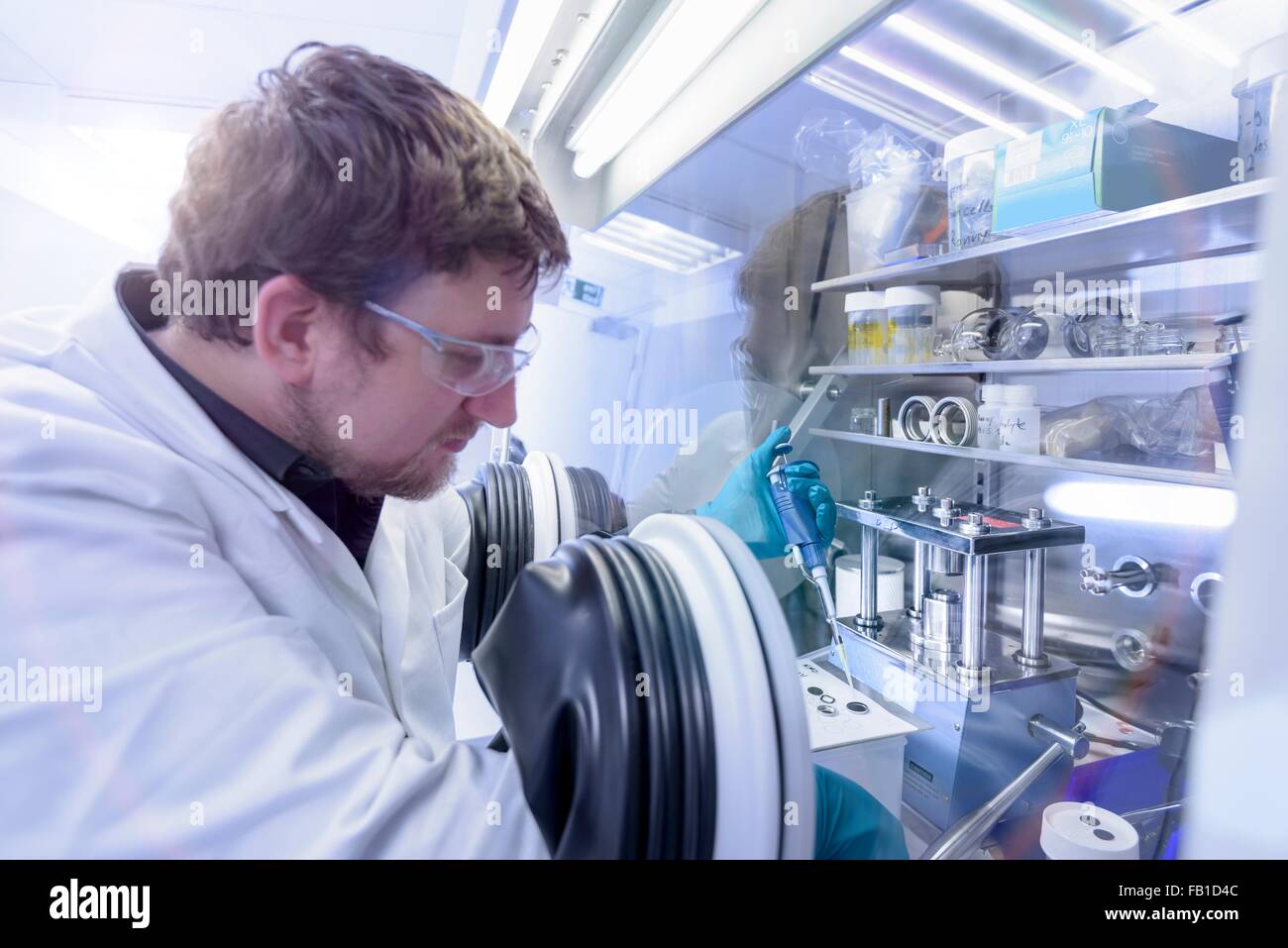 Assemblaggio dello scienziato agli ioni di litio batterie di test in camera a guanti in batteria in un centro di ricerca Foto Stock