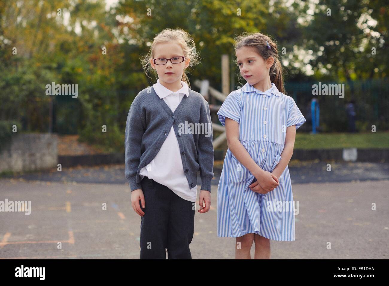 Ritratto di due studentesse elementari in piedi nel parco giochi a scuola Foto Stock