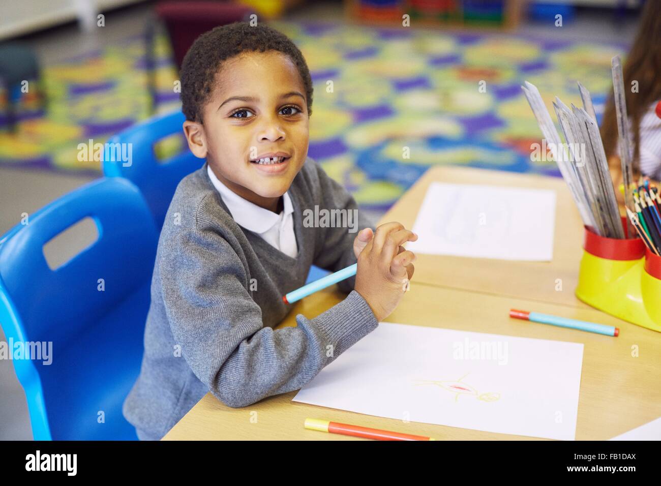 Ritratto di disegno del ragazzo al banco nella scuola elementare classroom Foto Stock