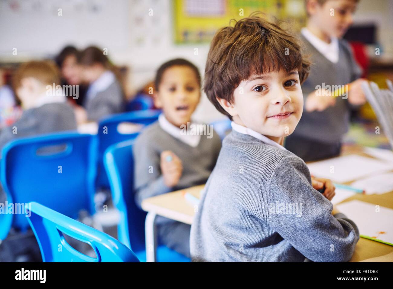 Ritratto di ragazzo guardando sopra la sua spalla nella scuola elementare classroom Foto Stock