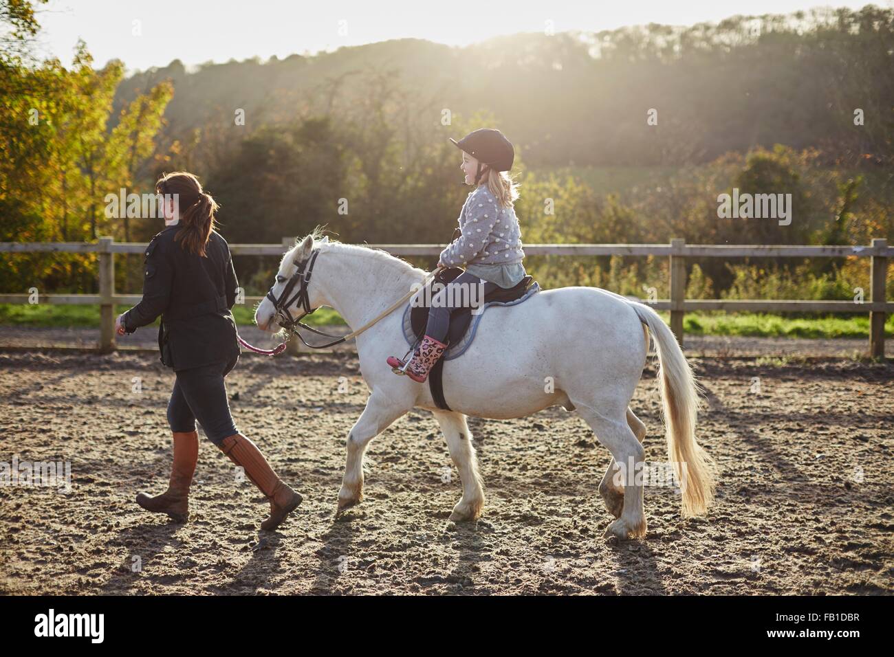 Istruttore ragazza leader di equitazione pony bianco in arena equestre Foto Stock