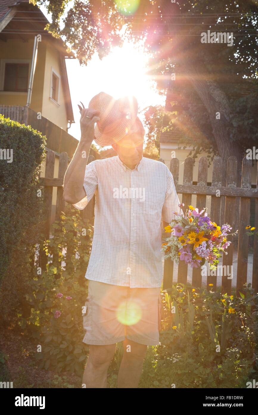 Senior l uomo nel giardino, tenendo mazzetto di fiori recisi freschi Foto Stock