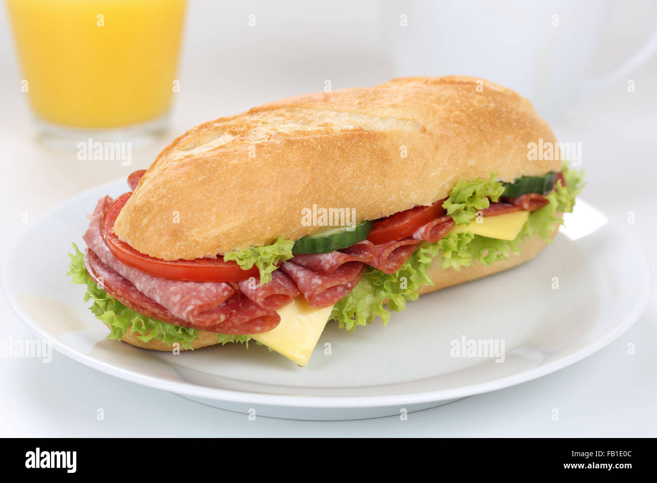 Sub deli sandwich baguette per colazione con salame prosciutto, formaggio, pomodori, lattuga e succo di arancia Foto Stock