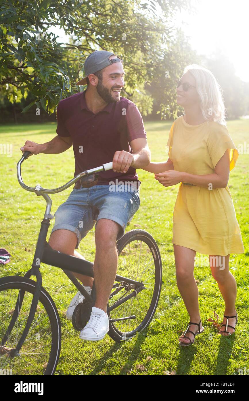 Coppia giovane in bicicletta nel parco soleggiato Foto Stock