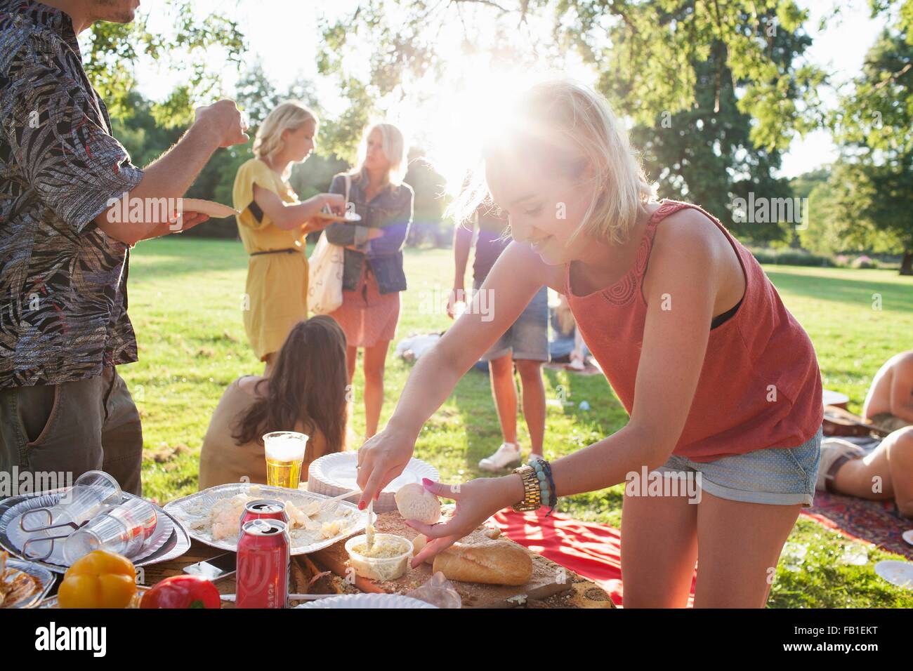 Giovane donna selezione di cibo al partito di gruppo picnic nel parco Foto Stock