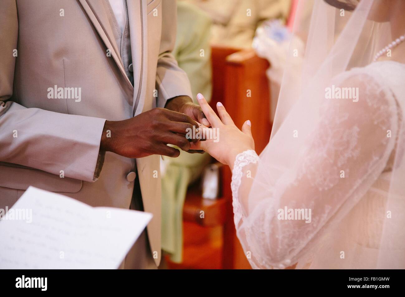 Vista ritagliata della sposo mettendo anello sul dito spose alla cerimonia di nozze Foto Stock