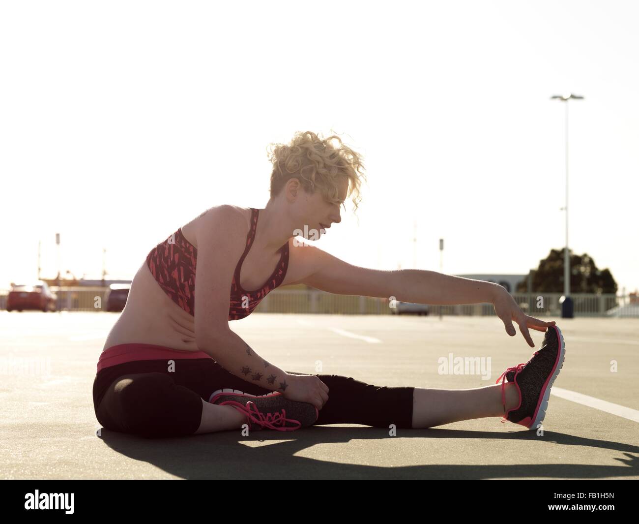 Giovane donna di toccare la sua dita mentre la formazione in parcheggio Foto Stock