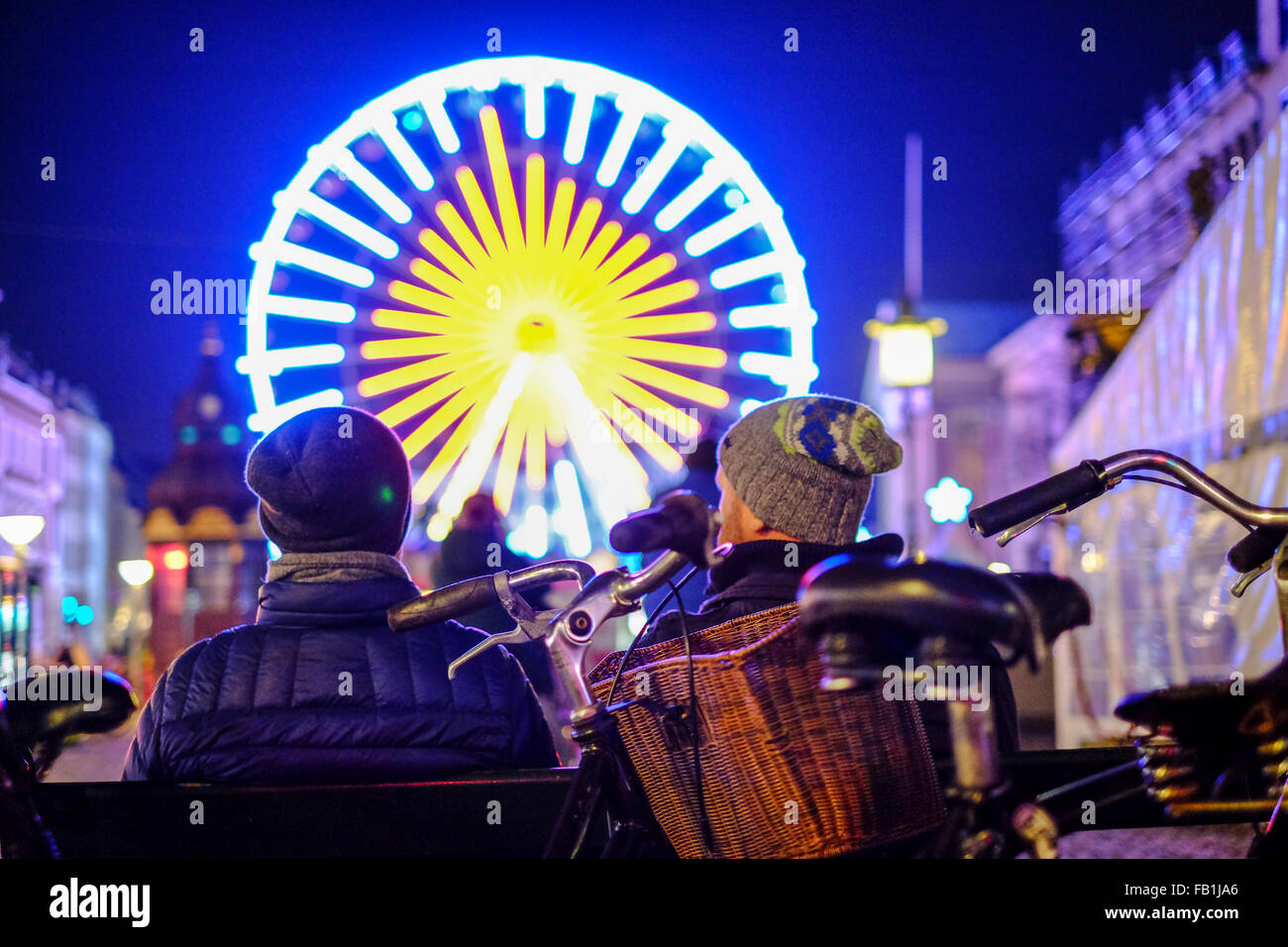 Un mercato di Natale ruota panoramica Ferris brilla nella notte mentre curiosi godere della fresca aria notturna dopo un giro in bicicletta. Foto Stock