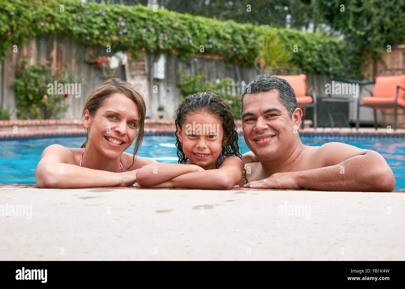 La testa e le spalle della ragazza in piscina con i genitori guardando sorridente della fotocamera Foto Stock