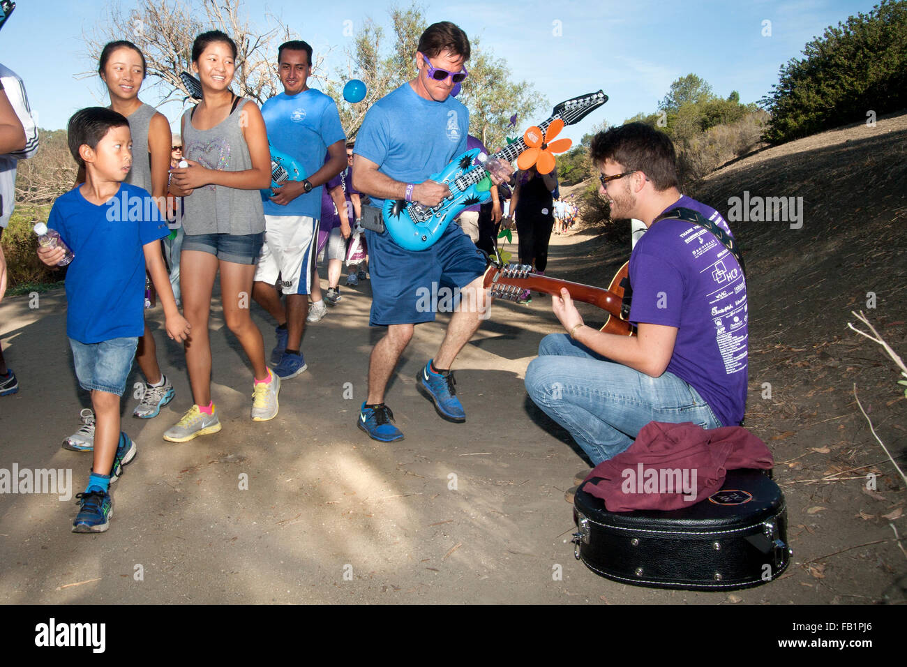 Musicisti volontari intrattenere i partecipanti in una raccolta fondi di beneficenza per le vittime dell'Alzheimer come si cammina in una Laguna Niguel, CA, parco. Nota viola commemorative T-shirt assegnati per le donazioni. Foto Stock