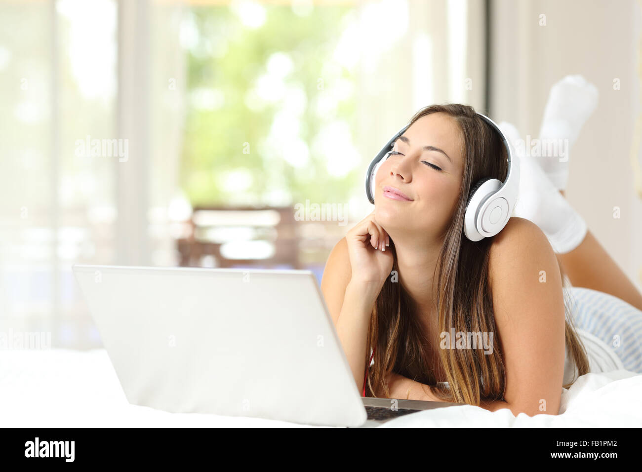 Ragazza di sentimento e di ascoltare la musica con le cuffie e il portatile  sul letto di casa Foto stock - Alamy