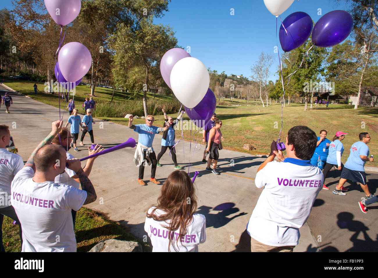 I partecipanti in una raccolta fondi di beneficenza a piedi per le vittime dell'Alzheimer attraversare la linea del traguardo come volontari allegria in una Laguna Niguel, CA, parco. Foto Stock