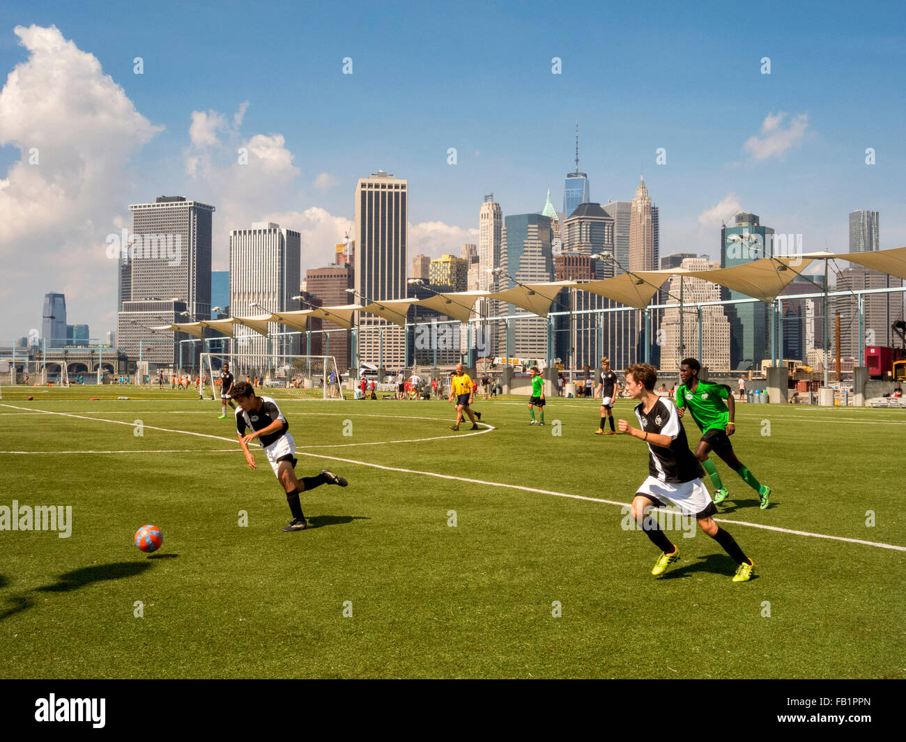 Squadre di calcio di giocare una partita nel ponte di Brooklyn Park in Brooklyn Heights, New York City, con lo skyline di Manhattan in background. Foto Stock