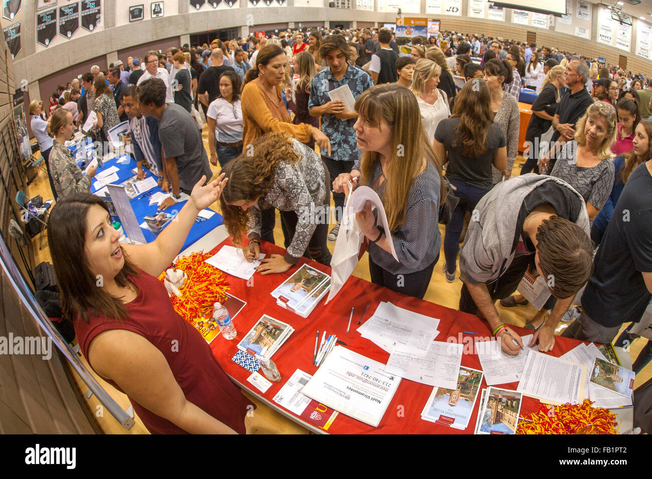 Multirazziale di alta scuola gli studenti frequentano una scuola in fiera un'Aliso Viejo, CA, scuola palestra. Nota college reclutatori presentano tabelle e agli studenti di prendere appunti. Foto Stock