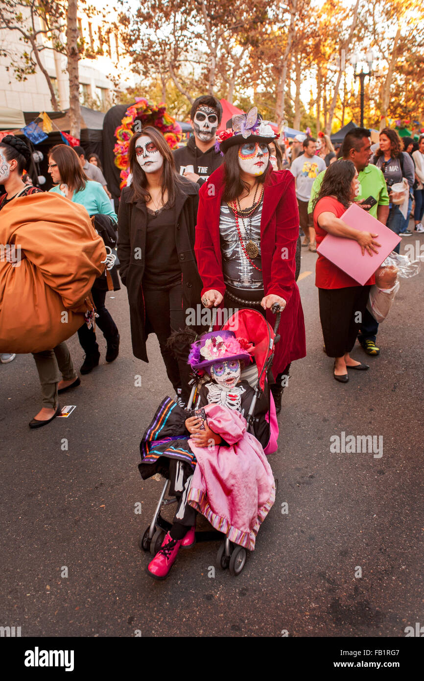 Indossando il trucco che assomiglia alla Calavera Catrina ('Dapper scheletro') carattere in Messico il giorno dei morti (Dia de Muertos), una famiglia di visite la celebrazione in ispanico Santa Ana CA. La vacanza si concentra sui raduni di familiari e amici a pregare per un Foto Stock