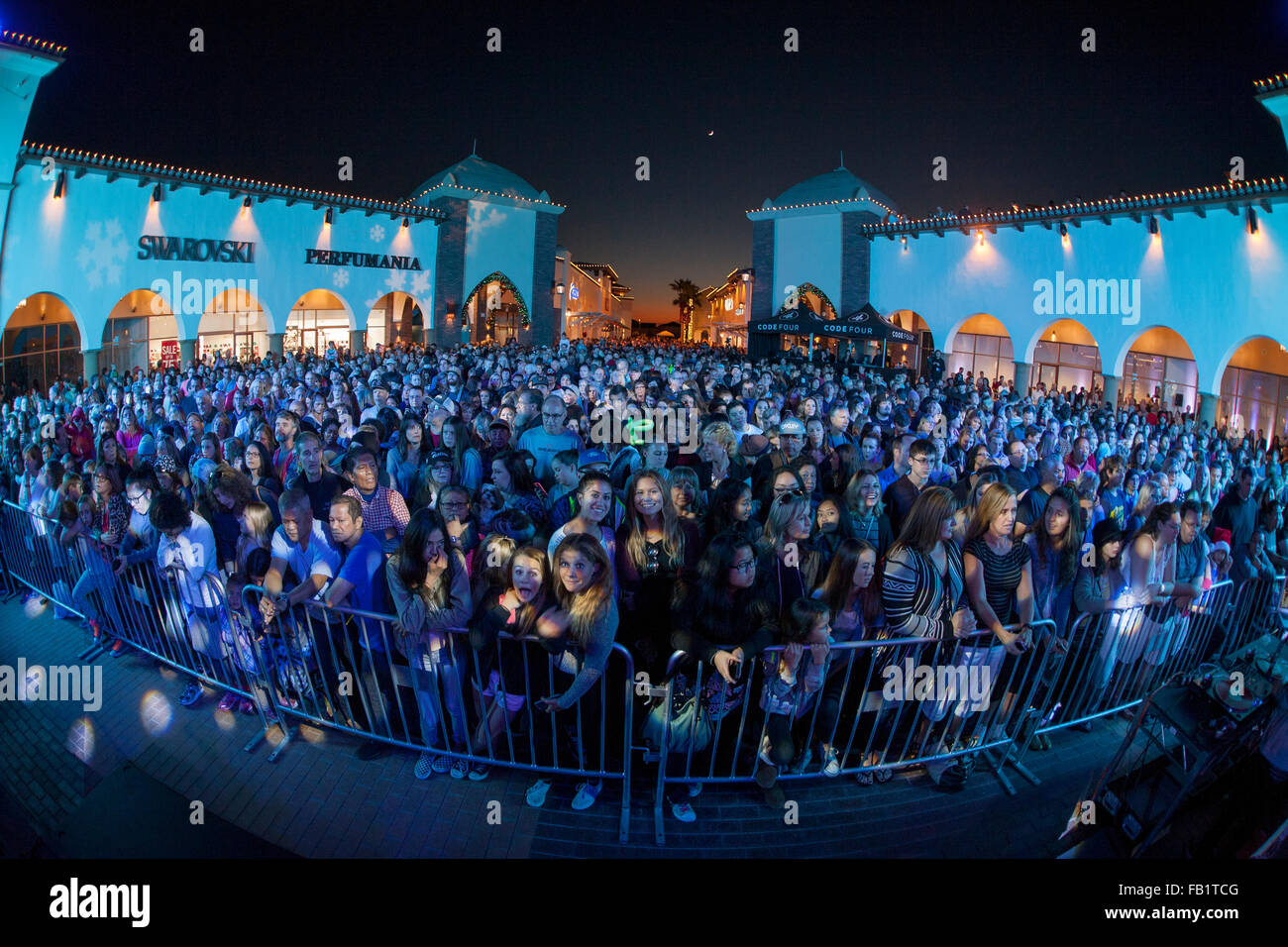 Un folto pubblico assiste una notte di Natale rock 'n' roll concerto a San Clemente, CA, shopping mall. Nota memorizza e barriera allo stadio. Foto Stock