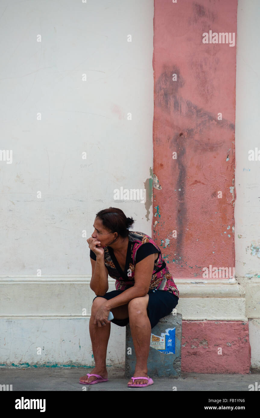 Il vecchio donna seduta e pensando di fronte a una parete Foto Stock