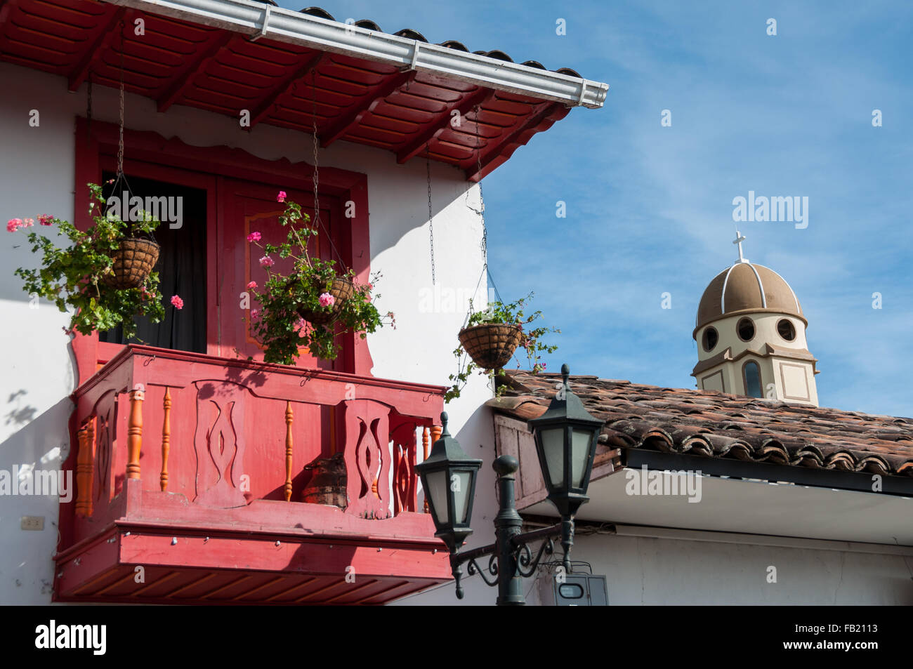 Balcone rossa e la torre di una chiesa di sfondo sotto il cielo blu Foto Stock