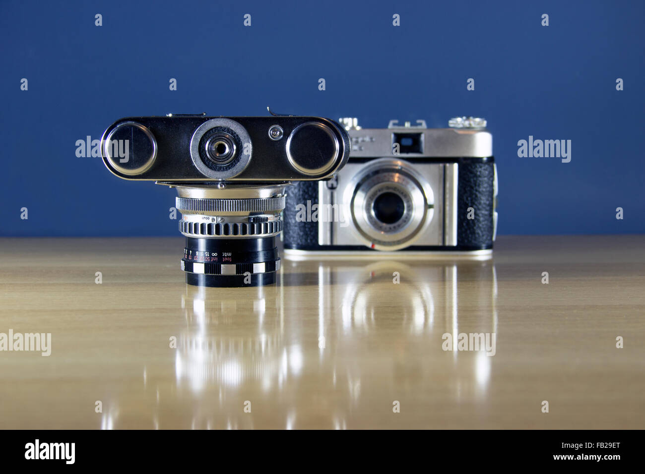 Due vecchio analogico 35mm telecamere presentate su un tavolo di legno Foto Stock