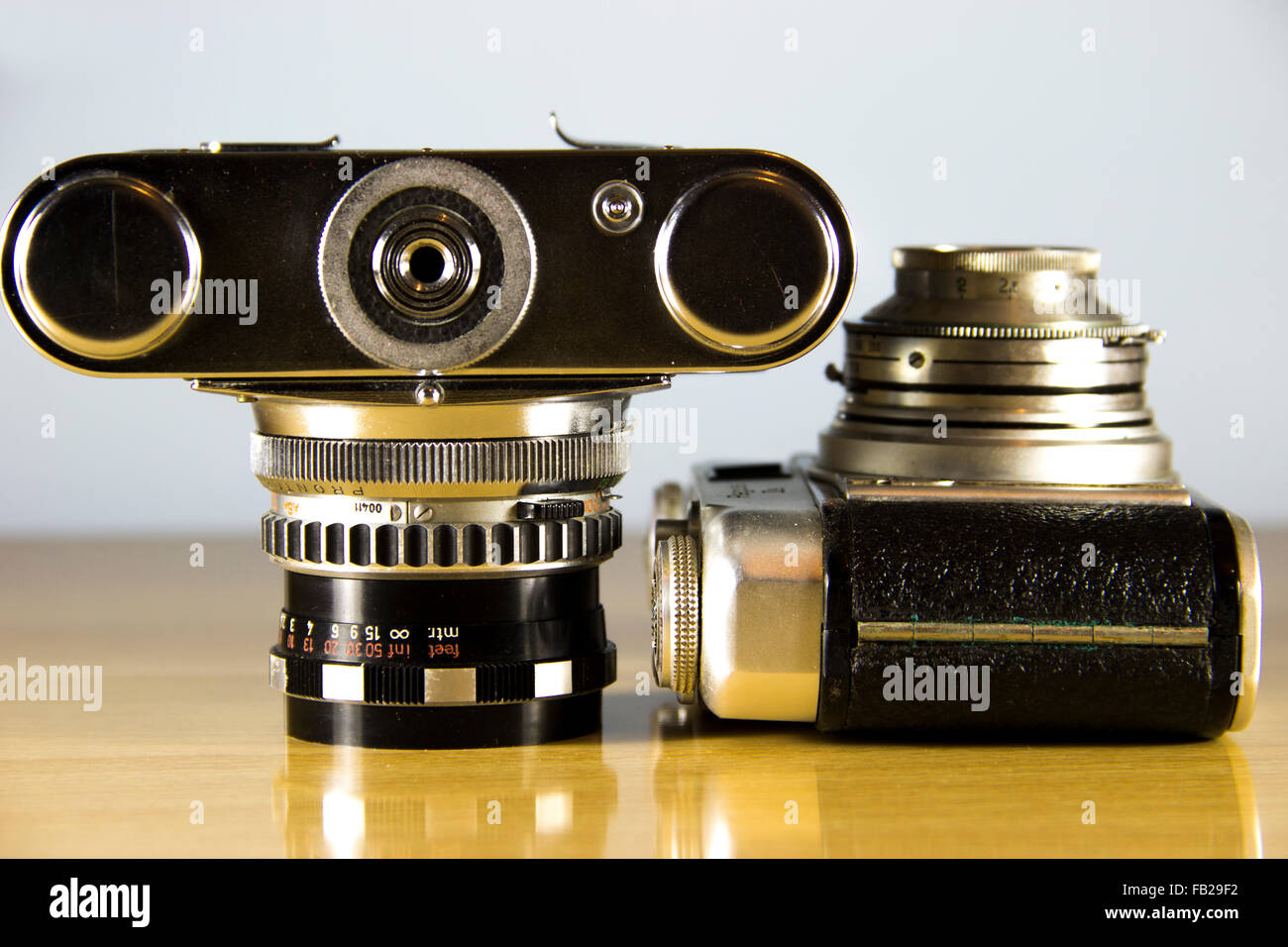 Due vecchio analogico 35mm telecamere presentate su un tavolo di legno Foto Stock