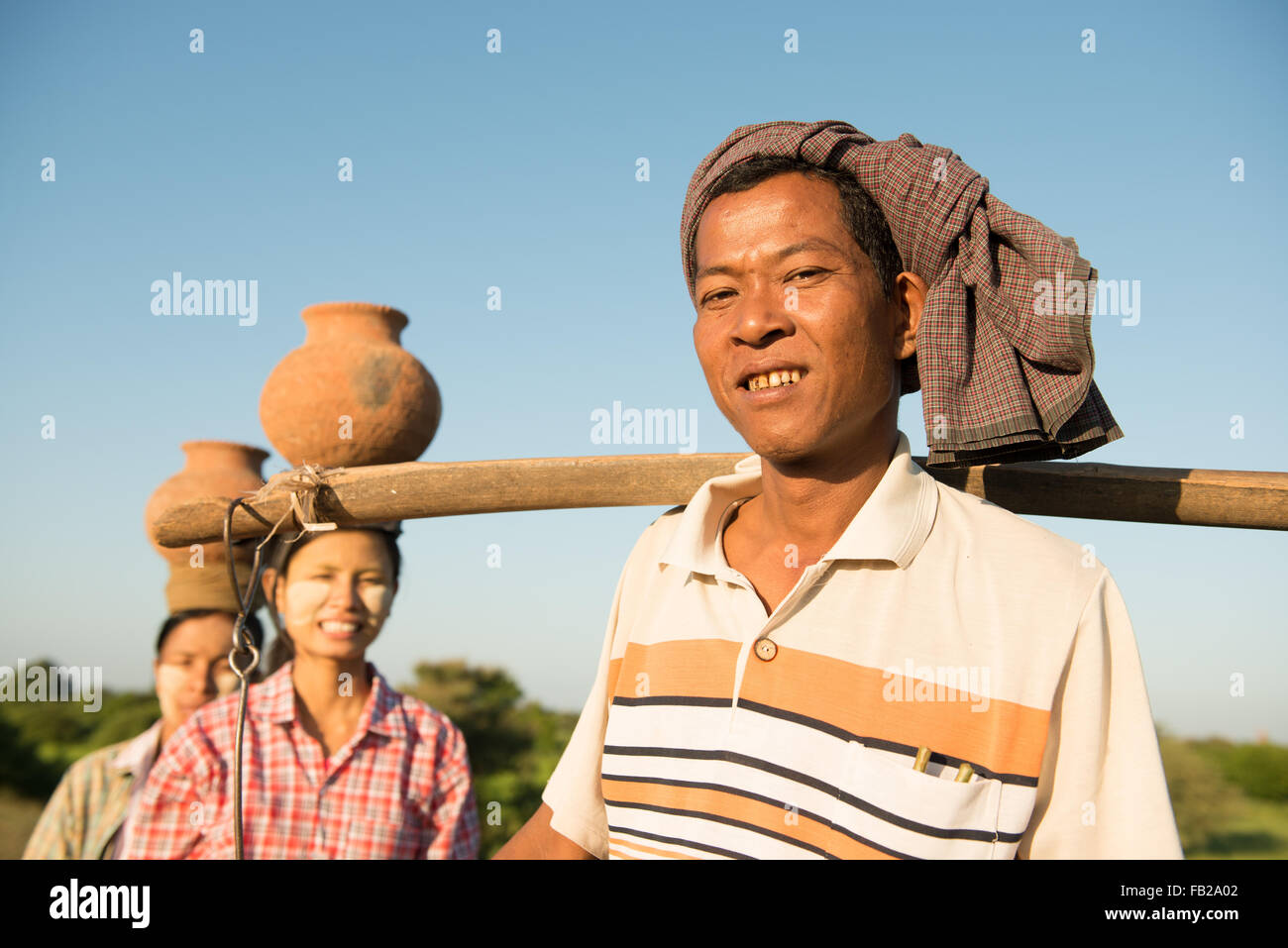 Ritratto di gruppo asiatico tradizionale birmana gli agricoltori che trasportano pentole di creta sulla testa, Bagan, Myanmar Foto Stock