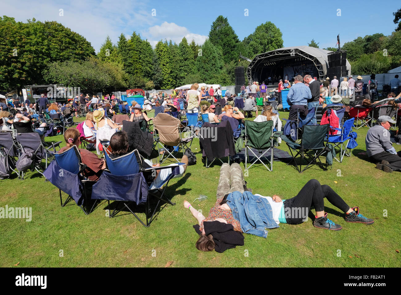 Inghilterra, Surrey, Tilford. Le persone a rilassarsi nel pomeriggio di sole mentre ascolto di una band al Weyfest music festival Foto Stock