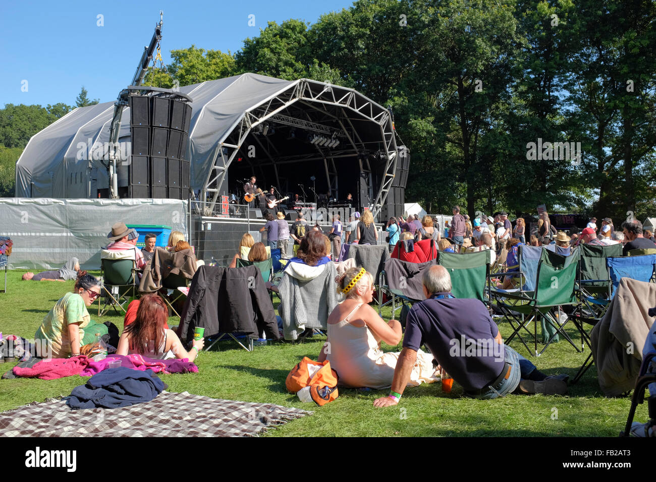 Inghilterra, Surrey, Tilford. Le persone a rilassarsi nel pomeriggio di sole mentre ascolto di una band al Weyfest music festival Foto Stock