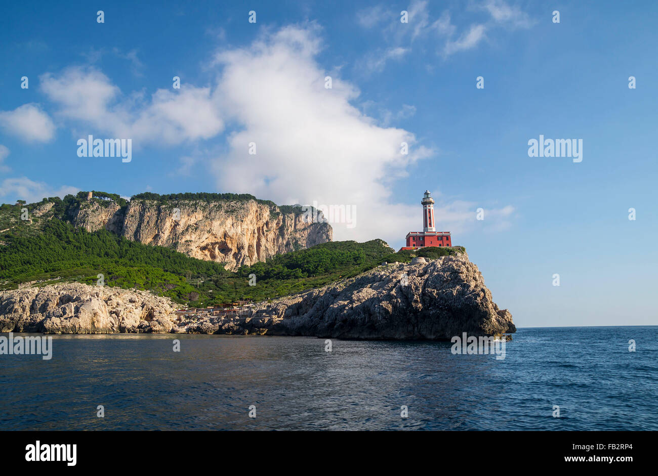 Faro di Punta Carena sulle rocce costiere al Mar Mediterraneo in Isola di Capri, visto da una barca a motore tour. Foto Stock