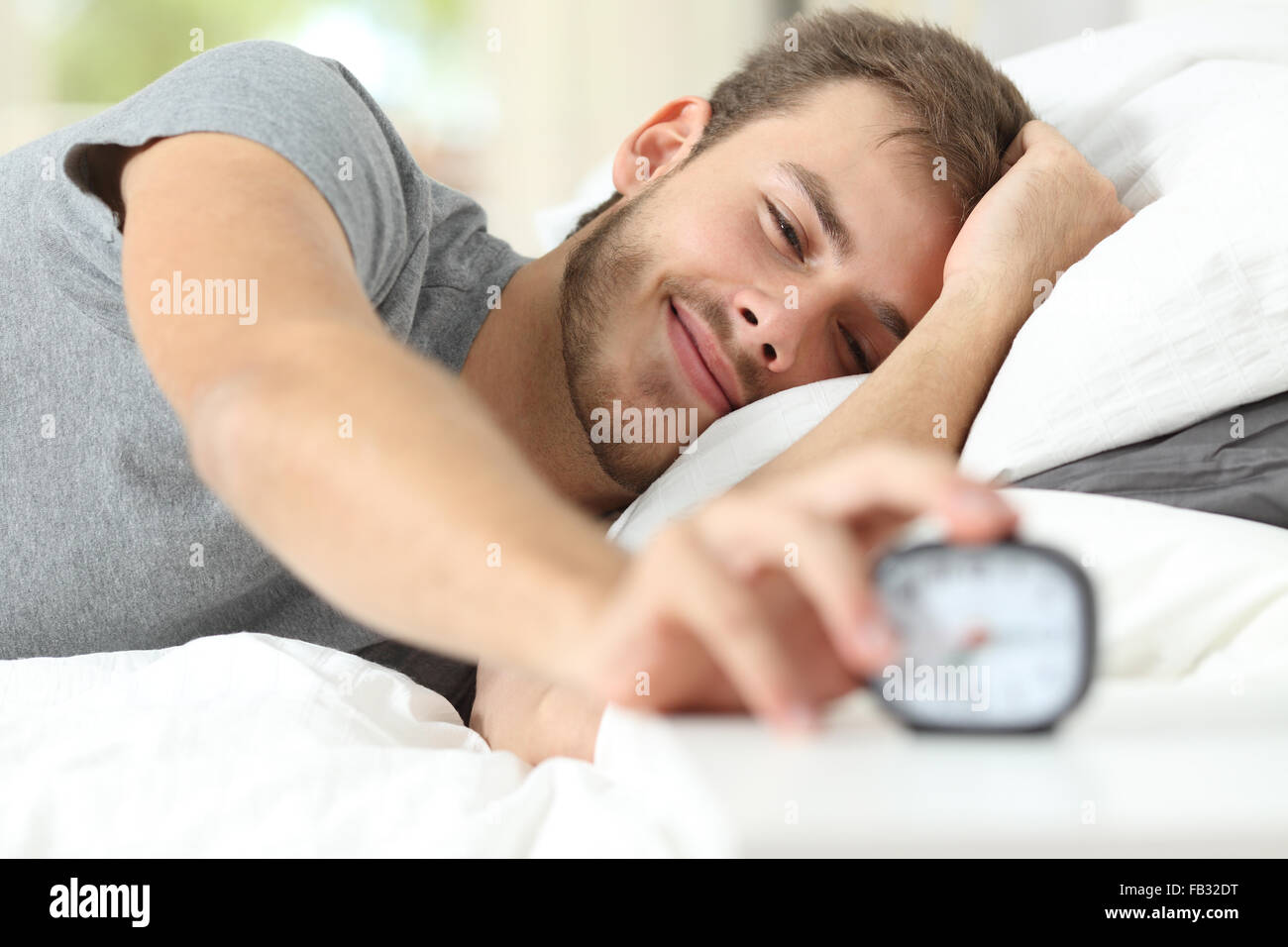 Happy wake up di un uomo felice giacente sul letto e arresto di sveglia Foto Stock