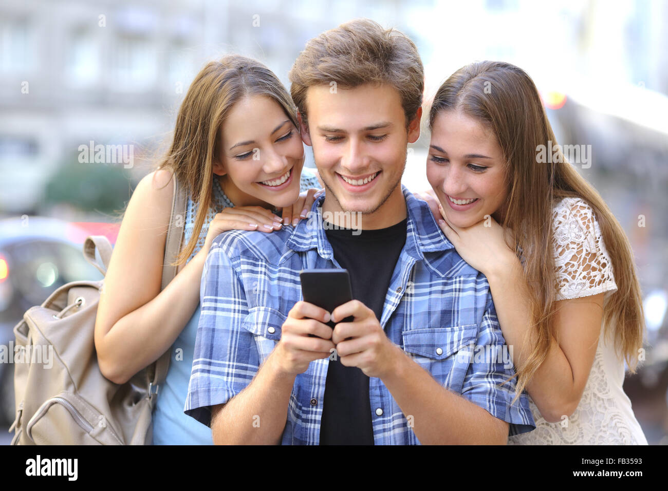 Simpatici amici condivisione di supporti multimediali in uno smart phone in strada Foto Stock