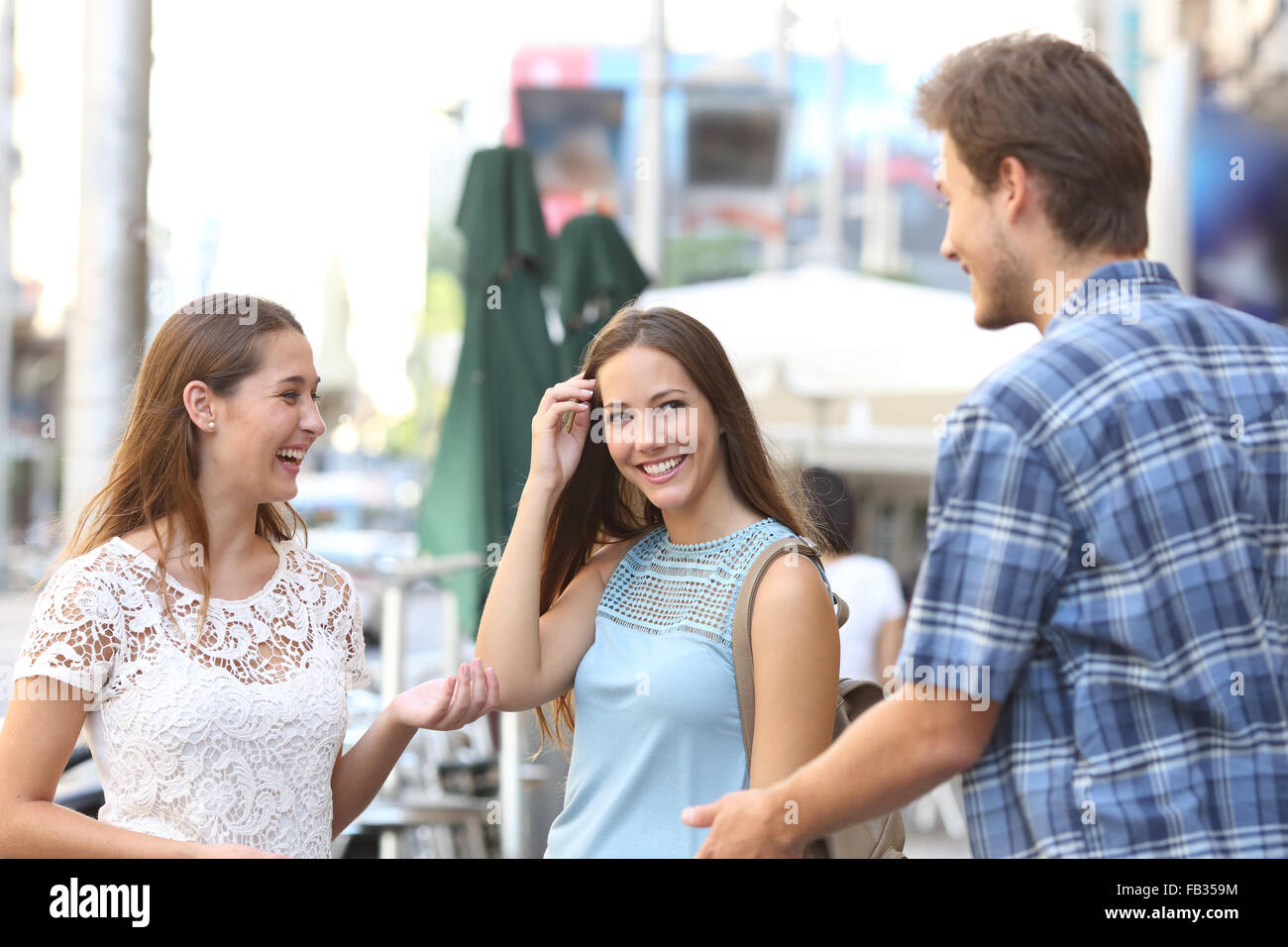 Candida ragazza con un amico flirtare con un ragazzo in strada Foto Stock