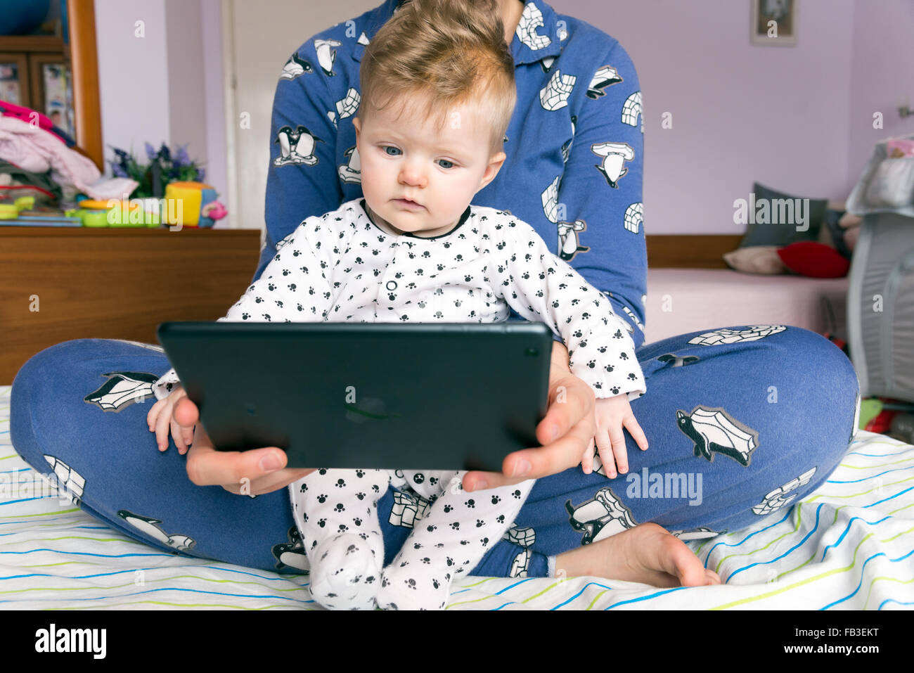 Sei mesi baby guardando lo schermo di iPad con sua madre Foto Stock