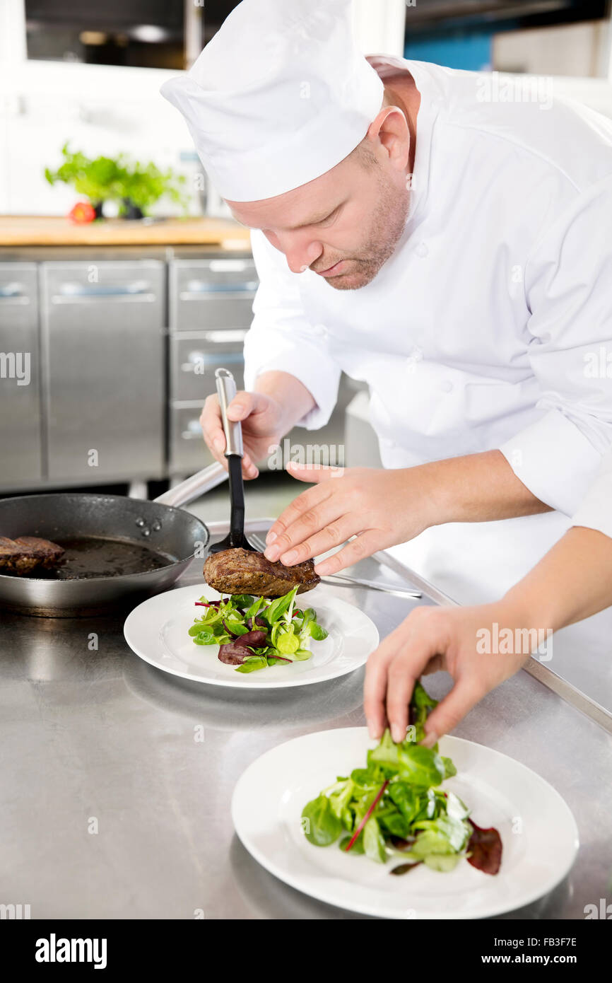 Professionale chef preparare piatto bistecca al ristorante Foto Stock
