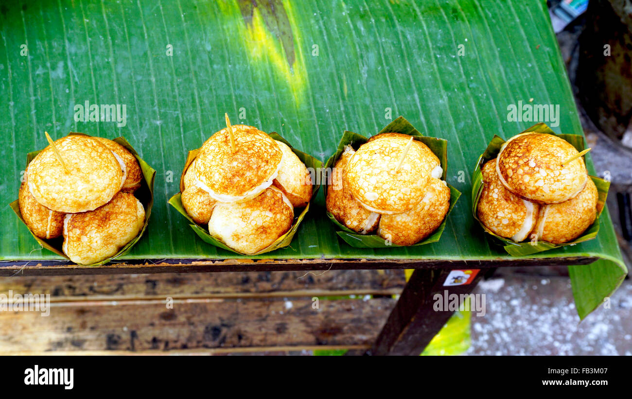 Dolce e Salato Coconut-Rice grigliate hotcakes, noce di cocco Torta di Riso sulla banana imballaggio, dessert asiatici, tailandese, Thailandia, Luang Prab Foto Stock