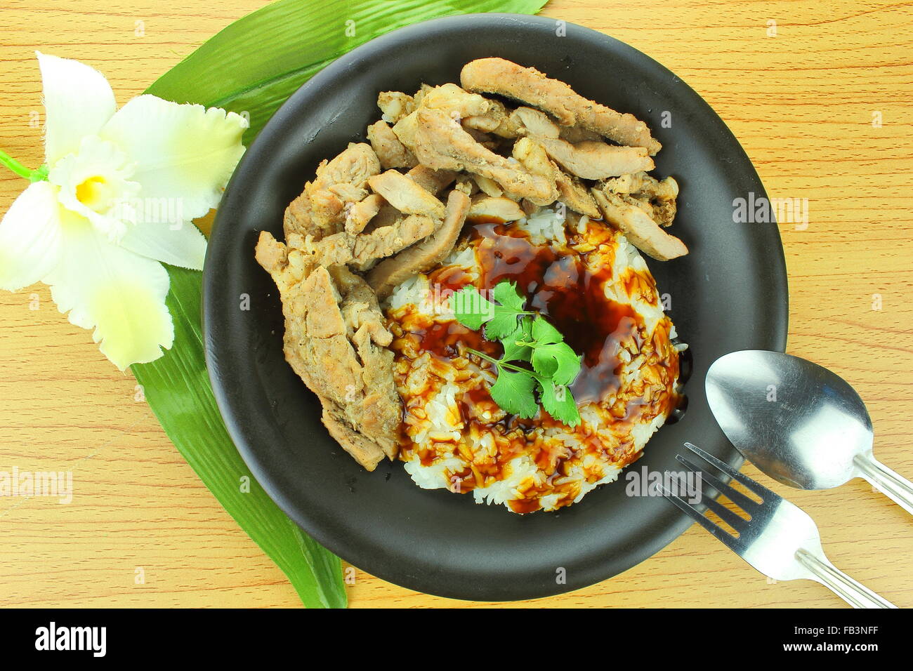 Bistecca di carne di maiale con riso e salsa teriyaki con cucchiaio e forchetta Foto Stock