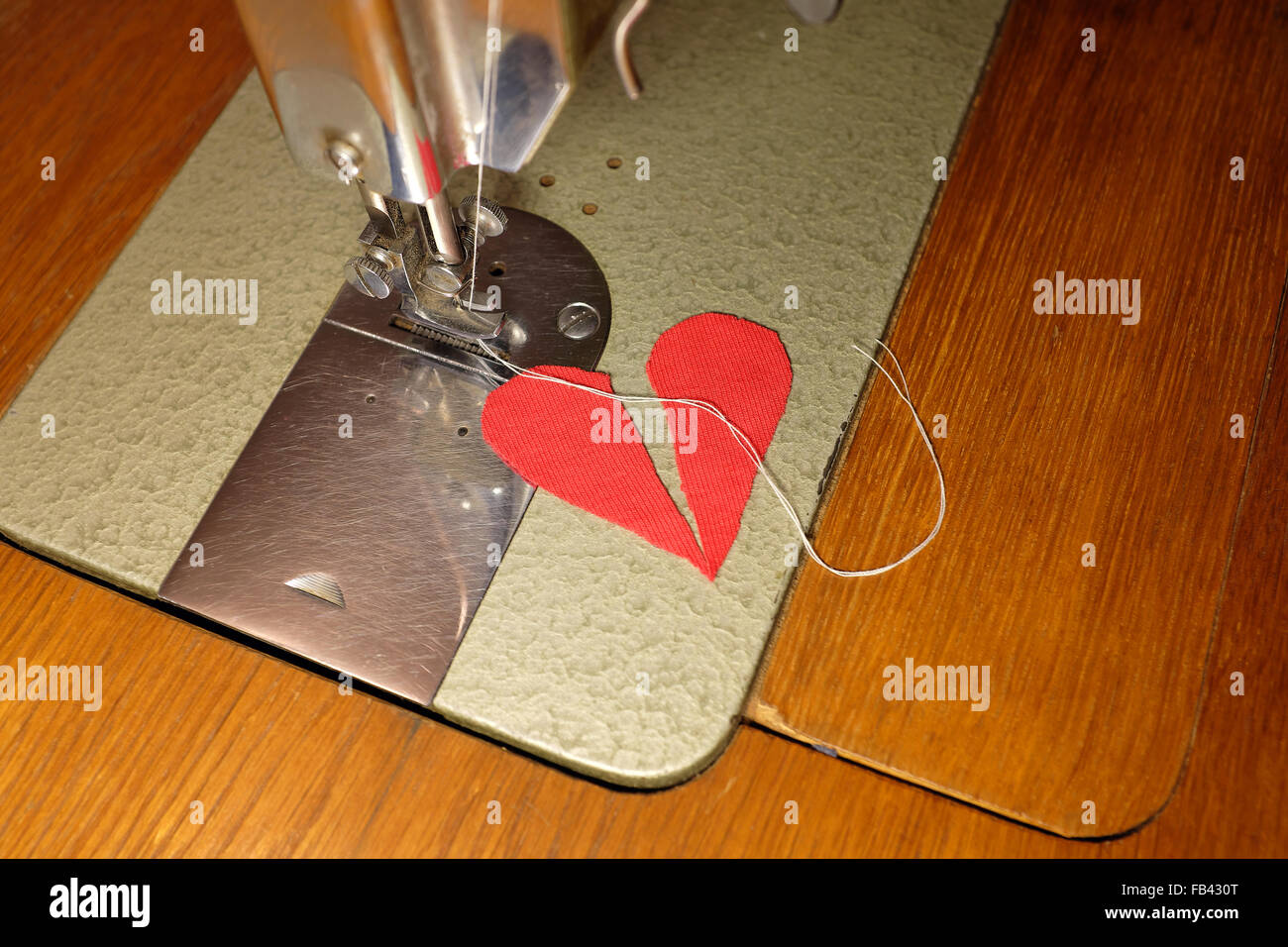 Sarto tentare di cucire due metà del cuore spezzato insieme, amore che non finisce mai concetto Foto Stock