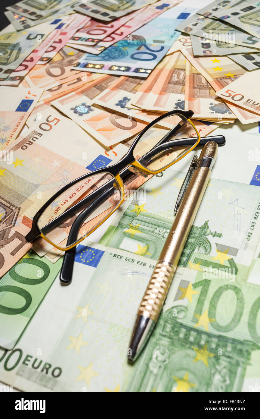 Penna e occhiali con banconote in euro. Profondità di campo Foto Stock