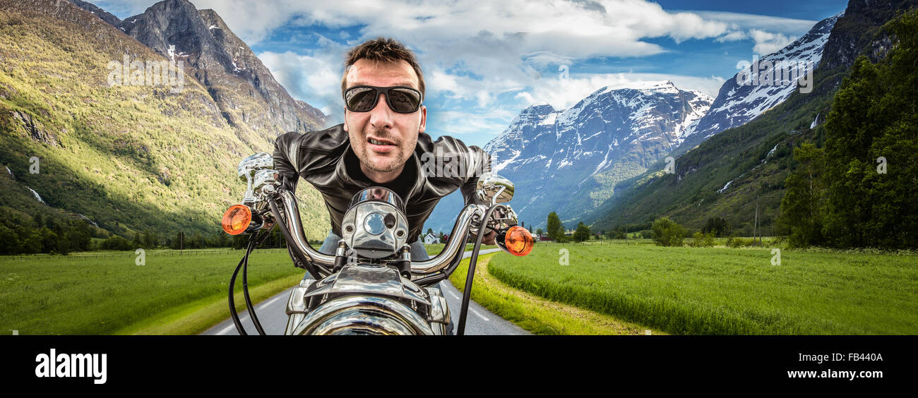 Funny Biker in occhiali da sole e giacca di pelle racing sulla serpentina di montagna. Filtro applicato in post-produzione. Foto Stock Funny Biker in occhiali da sole e giacca di pelle racing sulla serpentina di montagna. Filtro applicato in post-produzione. Foto Stock