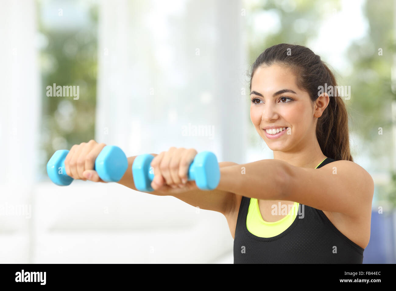 Felice ragazza fitness praticando sport facendo pesi a casa Foto Stock