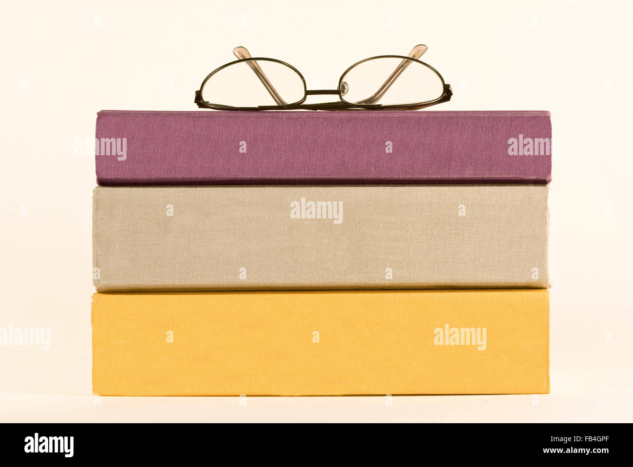 Tre libri impilati con spine vuota e un paio di occhiali sulla parte superiore Foto Stock